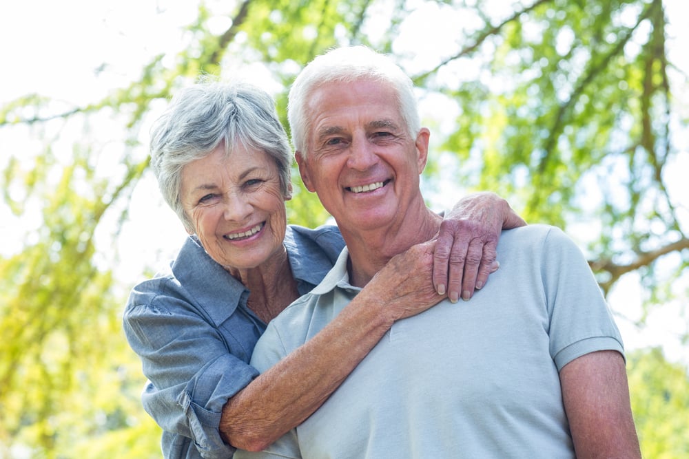 Happy old couple smiling in a park on a sunny day Happy old couple smiling in a park on a sunny day